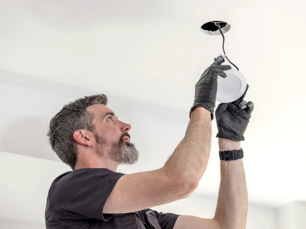 Kieran from LED Solutions fitting an LED downlight into a white ceiling