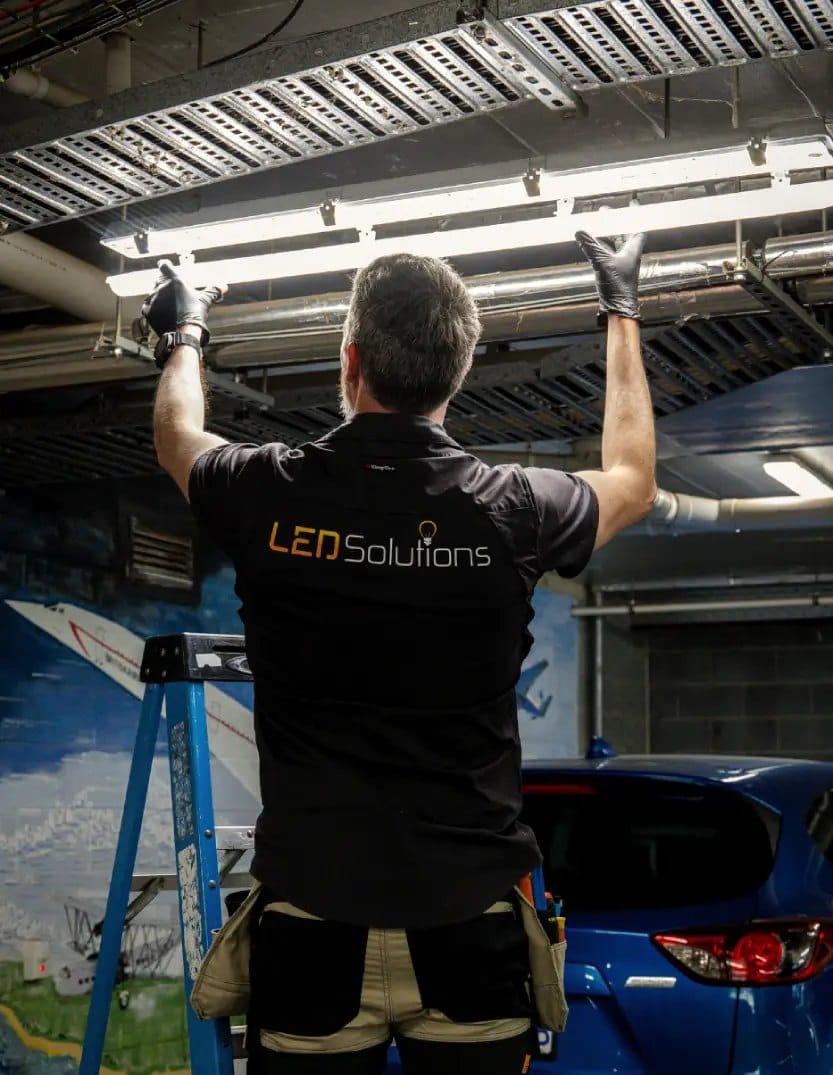 Kieran from LED Solutions fitting a batten light in a Canberra car park