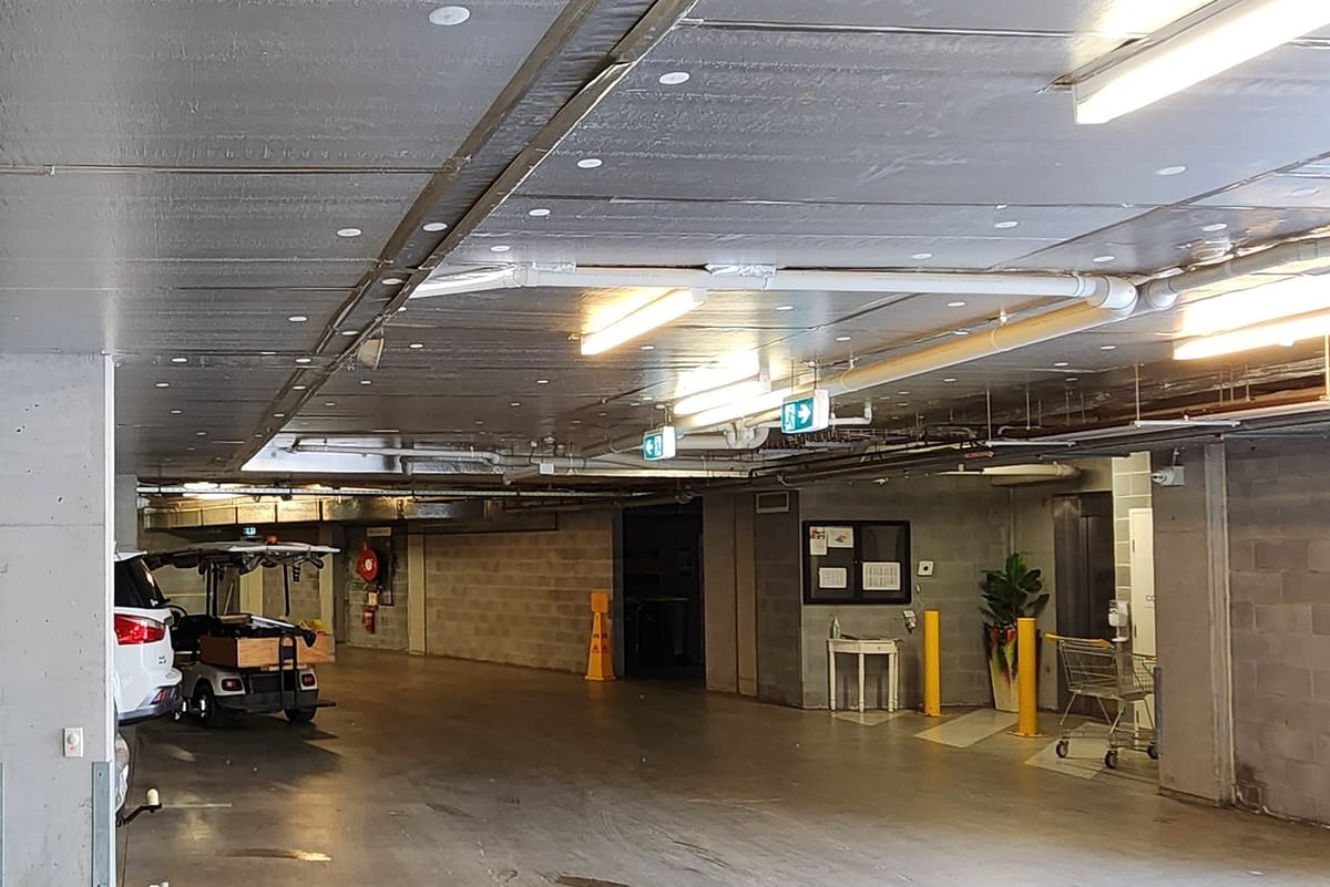 An empty underground car park in a Canberra strata building with every batten and downlight on