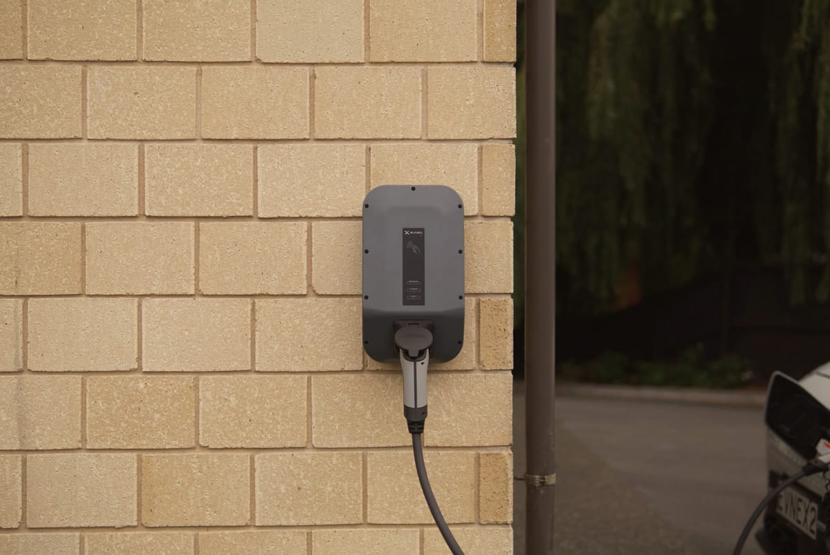 An electric car charger mounted on a pale brick wall