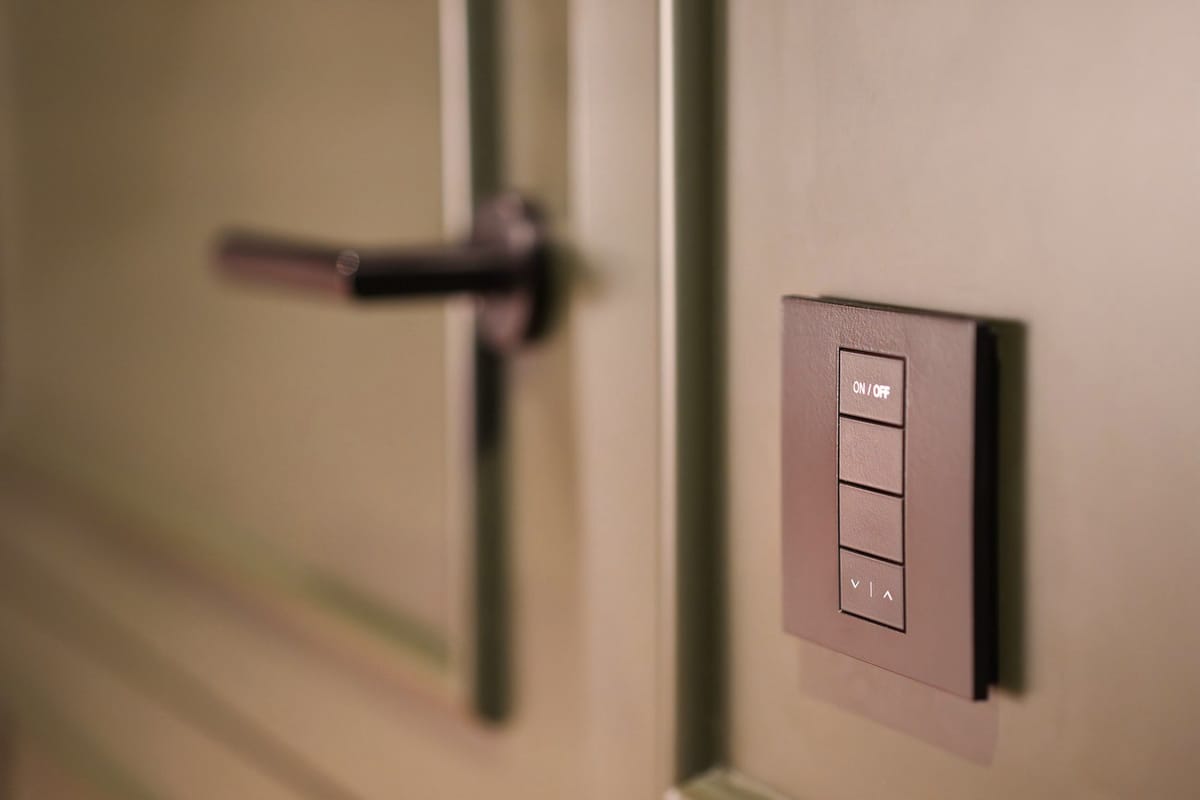 A lighting keypad on the wall beside a door, with on, off and dimming buttons