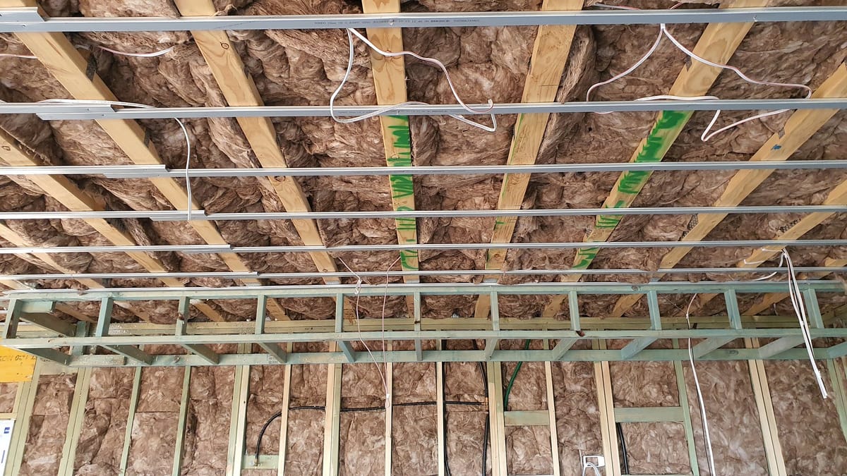 A ceiling at rough-in stage, with battens, insulation and cabling in place before it is lined
