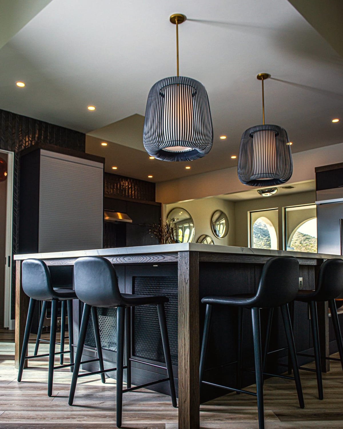 A kitchen island at night under pendant lights and downlights