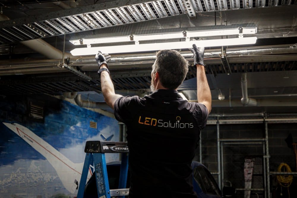 Kieran from LED Solutions fitting a batten light under the cable trays of a car park