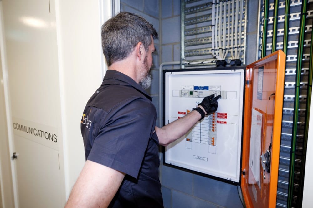 Kieran checking a switchboard in a building’s communications room